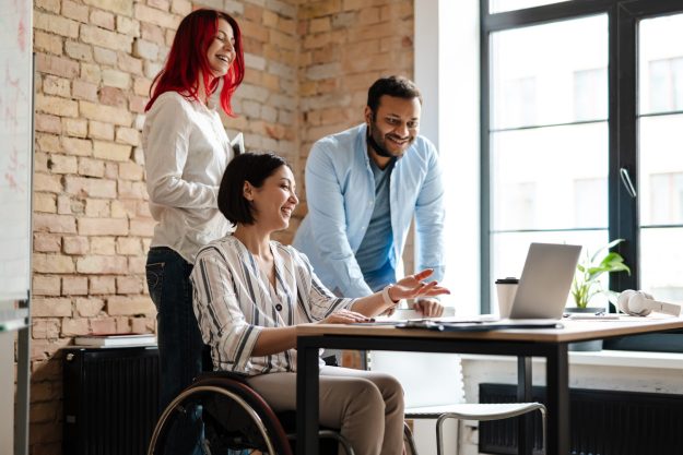 Multiracial smiling three colleagues talking and working with la